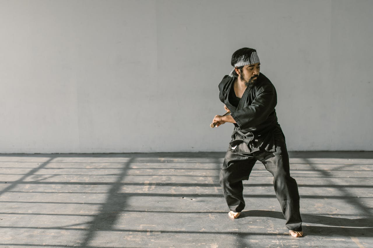 Services Martial artist in black gi training indoors, showcasing skilled discipline.