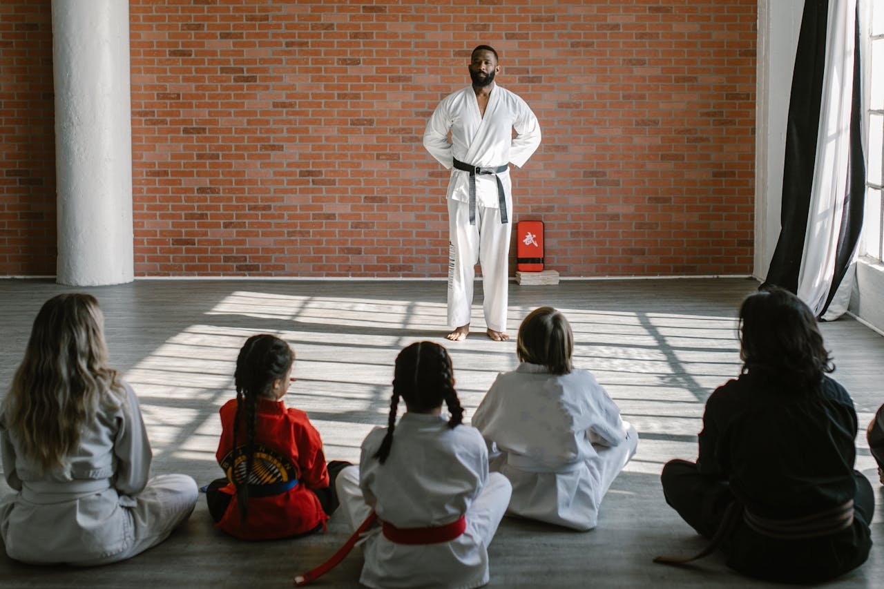 Home Young students in gis learn martial arts under the guidance of a black belt sensei in a dojo setting.